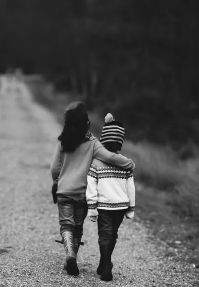 Two children walking arm in arm down a path